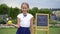 Happy little schoolgirl with a chalkboard outdoor