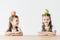 happy little schoolgirls with apple and pear on heads sitting at table