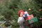 Happy little smiling girl in red cap with Christmas gift boxes standing near by spruce. Holiday celebrate concept