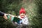 Happy little smiling girl in red cap takes a given box with a gift for Christmas. Kid standing near by spruce. Holiday celebrate