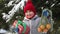 Happy little smiling girl standing near by spruce, holding gift box, tangerines