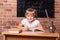 Happy little student girl sitting at a school desk and studying math. The child is doing homework. Preschool education, self