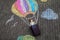 Happy little toddler girl flying in hot air balloon painted with colorful chalks in rainbow colors on ground or asphalt