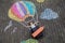 Happy little toddler girl flying in hot air balloon painted with colorful chalks in rainbow colors on ground or asphalt