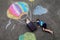 Happy little toddler girl and kid boy flying in hot air balloon painted with colorful chalks in rainbow colors on ground