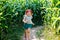 Happy little toddler girl playing on corn labyrinth field on organic farm, outdoors. Funny child hild having fun with