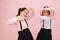 Happy little twin schoolgirls making arm and hand frames. Over pink