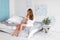 Happy long haired pregnant woman in white greek style bedroom interior