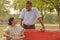 Happy looking retired senior Indian man and woman couple, sitting on a red bench, smiling and looking at each other in a park