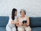 Happy lovely Asian senior woman, mother white hair and pretty young female, daughter pointing and looking at tablet screen.