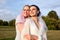 Happy lovely bride in white dress with white veil and bridesmaid in blue dress with pink veil in summer park. Young