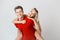 Happy lovely cheerful young couple in red casual look is hugging and smiling looking at camera on white background