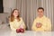 Happy lovely couple in yellow holding cups, eating red apples and sitting by the table