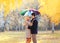 Happy loving couple with colorful umbrella together in warm sunny day over yellow flying leafs