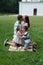 Happy loving european family in the park on the lawn in summer. Husband kisses his wife, brother kisses little sister. Concept of