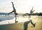 Happy loving family of mother and daughter having fun making acrobatic handstand on the beach at sunset