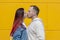 Happy loving young couple - girl and guy kissing gently on a Sunny summer day walk on a yellow background.