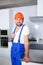 A happy male builder, standing in the kitchen and smiling cute. Indoors in the apartment.