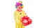 A happy male clown holding a red present