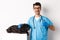 Happy male doctor veterinarian examining cute black dog pug, showing thumb up in approval, satisfied with animal health