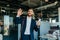 Happy male office worker in suit entering office space smiling and waving to colleagues, copy space