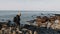 Happy male photographer stepping on rocky beach, taking pictures of stunning sunny Normandy shore cliffs slow motion.