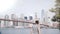 Happy male tourist comes up to famous New York skyline at Brooklyn Bridge river bank fence, feeling joyful and ecstatic