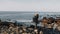 Happy male tourist standing on rocky Etretat beach, taking photos of stunning sunny Normandy white cliffs slow motion.