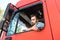 Happy male truck driver inside his red cargo truck