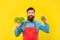 Happy man in apron holding fresh lettuce and juice bottle yellow background, juice barkeeper