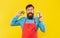 Happy man in apron holding limes and juice bottle yellow background, juice barkeeper