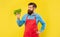 Happy man in apron looking at fresh leaf lettuce yellow background, greengrocer