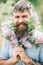 Happy man with beard and lilac blossom. Bearded man smile with lilac flowers on sunny day. Hipster enjoy scent of