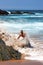 Happy man being splashed by a wave on the beach in Suances, Spain