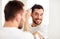 Happy man brushing hair with comb at bathroom