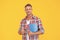 Happy man in casual giving thumb holding school books yellow background, education