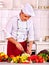 Happy man in chef hat cooking fresh vegetable salad.