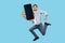 Happy man in denim outfit flying and jumping in air and showing big mobile empty screen