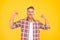 Happy man flex strong arms listening to music in modern headphones yellow background, sound power