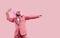 Happy man in funky party suit, funny clown wig and sunglasses dancing on pink studio background