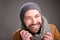 Happy man with hat and scarf posing against gray wall