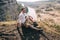 Happy Man hiker sitting at mountain top and looking at scenic landscape