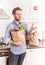 Happy man holding paper grocery shopping bag in the kitchen