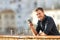 Happy man holding a phone looking at camera at sunset