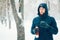 Happy man holding thermos in park with snow. Young man drinking hot drink in forest in winter time