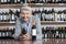 Happy Man Holding Wine Bottle While Leaning On Table