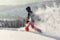 Happy Man with hood running in deep powder snow with snowshoes. Snow is spraying and splashing.