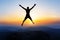 Happy man jumping for joy on the peak of the mountain, cliff at sunset. Success, winner, happiness