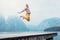 Happy man jumps on wooden pier at the mountain lake