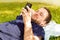 Happy man looking at mobile phone while laying on grass